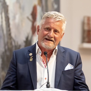 A photo of Mark Gregory speaking into a microphone.
