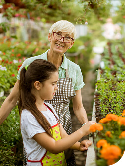 A lady and a young girl smiling in a greenhouse