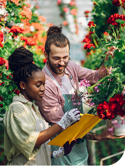 A man and woman smiling in a greenhouse