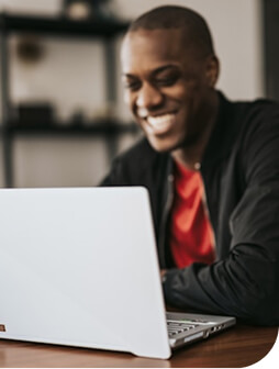 A man smiling while using a laptop