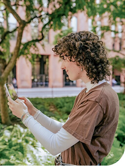 A person smiling taking photos on their phone outdoors